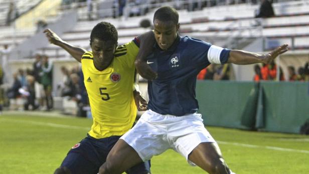 Zwei Fußballspieler im Zweikampf, einer im gelben Trikot Kolumbiens, der andere im blauen Trikot Frankreichs.