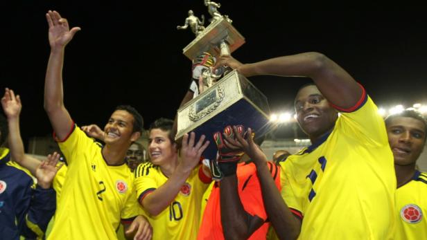 Kolumbianische Fußballspieler feiern mit einer Trophäe.