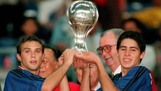 Zwei junge Männer halten eine silberne Trophäe in die Höhe.