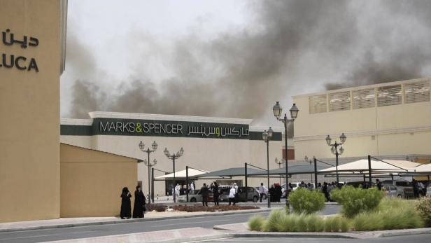 Rauch steigt über einem Marks & Spencer-Geschäft auf, während Menschen sich davor versammeln.