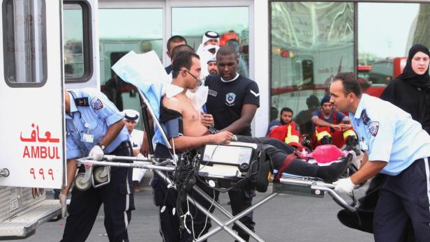 Sanitäter schieben einen Patienten mit Sauerstoffmaske auf einer Trage in einen Krankenwagen.