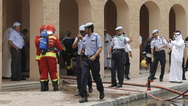 Feuerwehrleute und Polizisten stehen vor einem Gebäude mit Torbögen.