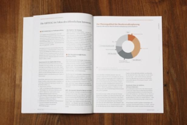 Asfinag/Nachhaltigkeitsbericht/identum Ein geöffnetes Buch liegt auf einem Holztisch und zeigt Text und ein Kreisdiagramm.