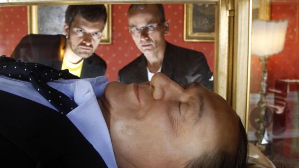 Zwei Männer betrachten eine Wachsfigur von Silvio Berlusconi in einem Museum.