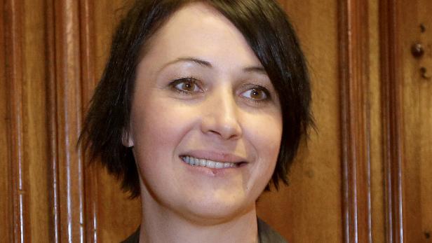 Porträt einer lächelnden Frau mit braunen Augen und dunklen, kurzen Haaren.