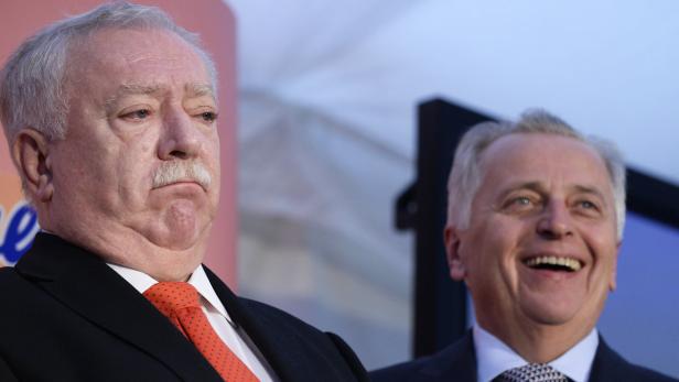 Zwei Männer in Anzügen stehen nebeneinander.