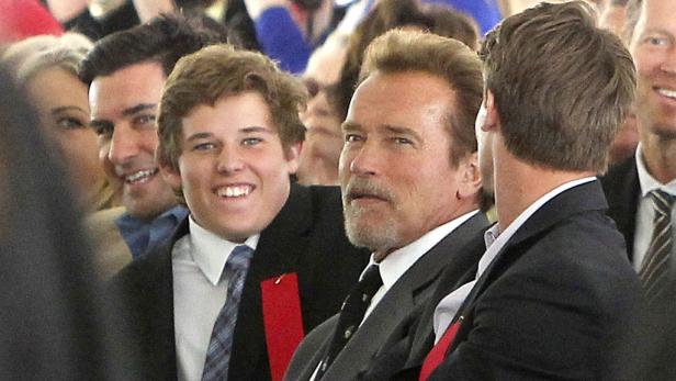 Arnold Schwarzenegger mit mehreren jungen Männern im Anzug.