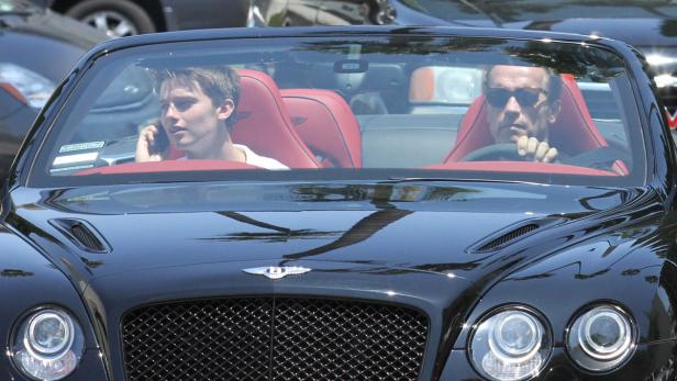 Arnold Schwarzenegger fährt mit seinem Sohn in einem schwarzen Bentley Cabriolet.