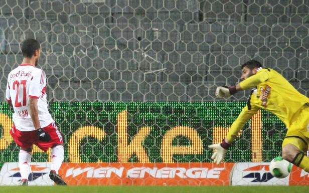Ein Fußballspieler von Red Bull steht vor dem Tor, während der Torwart den Ball abwehrt.