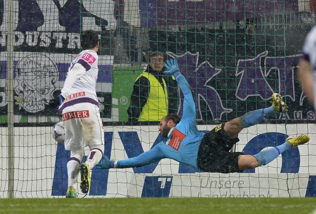 Ein Fußballtorwart hechtet, um einen Ball abzuwehren.