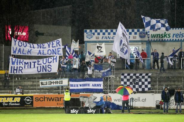 Fußballfans mit Fahnen und Transparenten unterstützen ihr Team im Stadion.