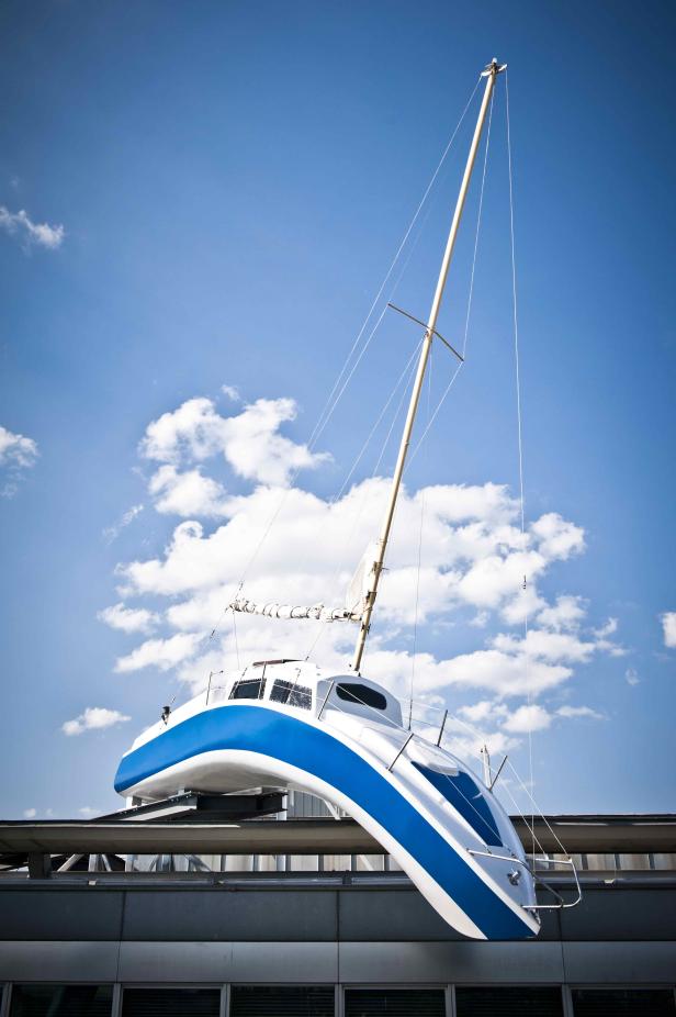 Ein blau-weißes Segelboot steht auf dem Dach eines Gebäudes.