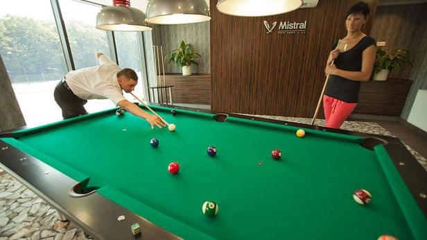 Ein Mann spielt Billard, während eine Frau zusieht.