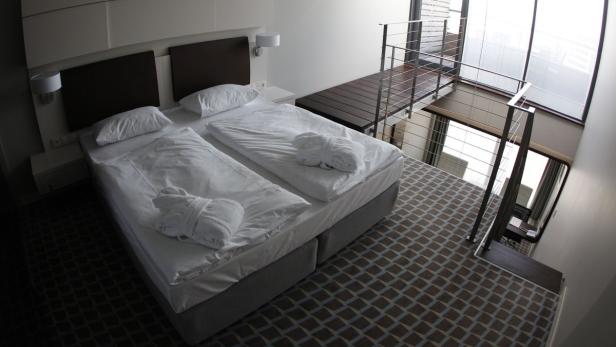 Ein Doppelbett mit Bademänteln in einem modernen Hotelzimmer mit Galerie.