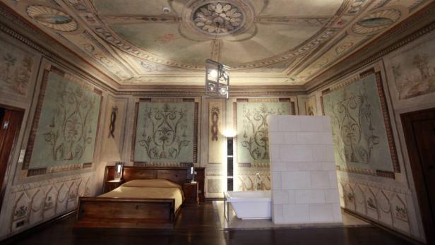 Ein Schlafzimmer mit bemalten Wänden und einer freistehenden Badewanne.