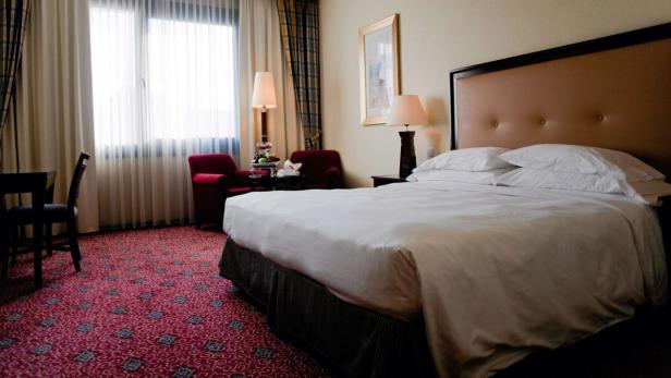 Ein Hotelzimmer mit einem großen Bett, Sesseln und einem Fenster.