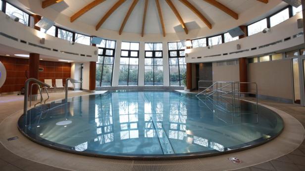 Ein rundes Schwimmbecken in einem hellen Raum mit großen Fenstern.