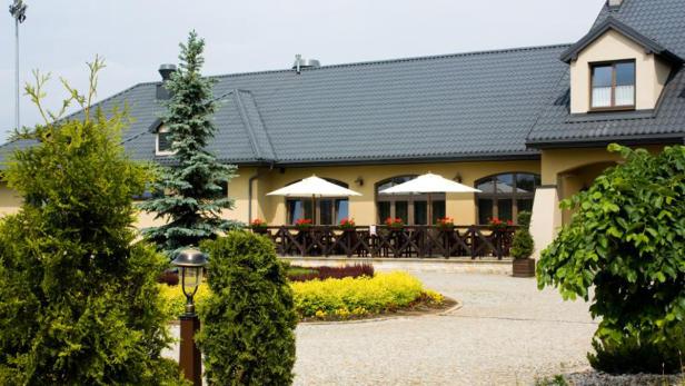 Ein zweistöckiges Gebäude mit einem grauen Dach und einer Terrasse mit Sonnenschirmen.