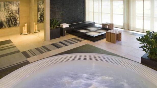 Ein Whirlpool in einem Wellnessbereich mit Sitzecke und Dekorationen.