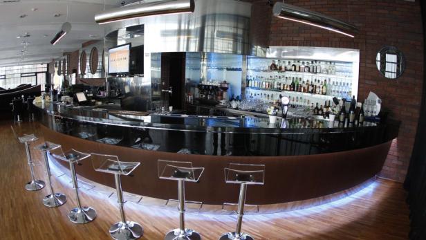 Eine Bar mit Barhockern und einer großen Auswahl an Getränken im Hintergrund.