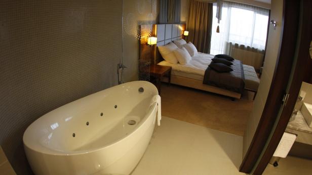 Ein Badezimmer mit einer freistehenden Badewanne und einem Schlafzimmer im Hintergrund.