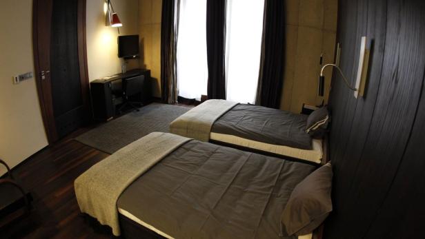 Ein Hotelzimmer mit zwei Einzelbetten, einem Schreibtisch und dunklen Holzvertäfelungen.