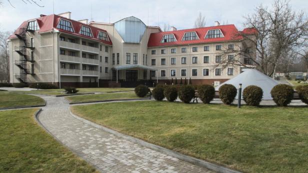 Ein großes Gebäude mit rotem Dach und gepflegtem Rasen davor.