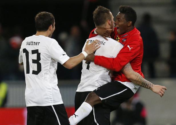 Drei Fußballspieler umarmen sich auf dem Spielfeld.