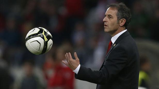 Ein Mann im Anzug jongliert mit einem Fußball.