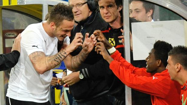 Fußballspieler gratulieren sich in der Nähe der Trainerbank.