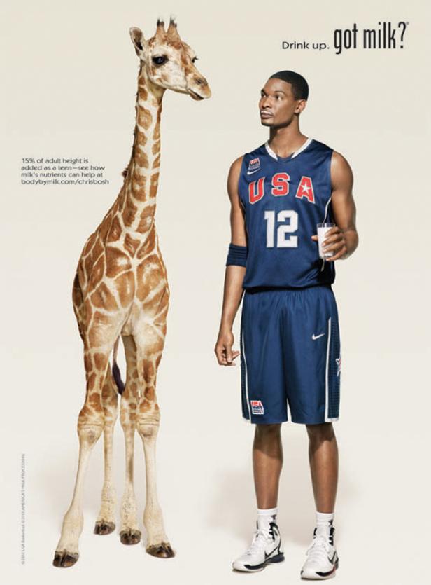 Chris Bosh, ein Basketballspieler, steht neben einer Giraffe und wirbt für Milch.