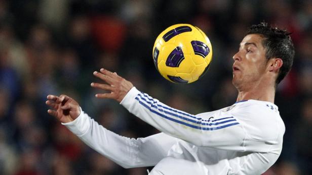 Cristiano Ronaldo köpft einen gelben Fußball.