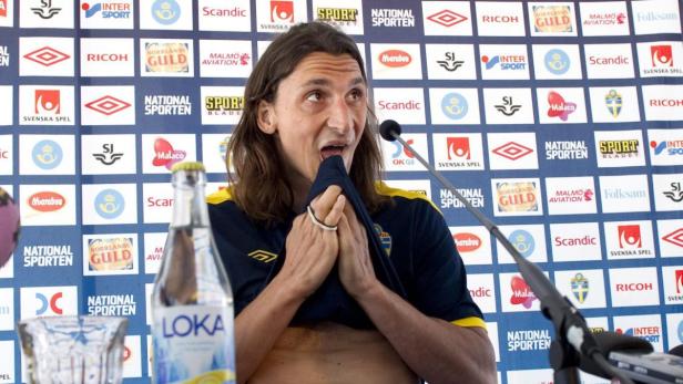 Zlatan Ibrahimović hält sein Trikot vor dem Mund bei einer Pressekonferenz.