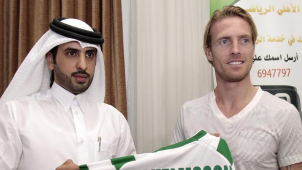 Ein Mann in traditioneller arabischer Kleidung und ein Mann mit blonden Haaren halten ein Fußballtrikot.