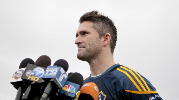 Ein Mann steht vor einer Gruppe von Mikrofonen und spricht.