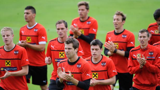 Eine Gruppe österreichischer Fußballspieler in roten Trikots klatscht Beifall.
