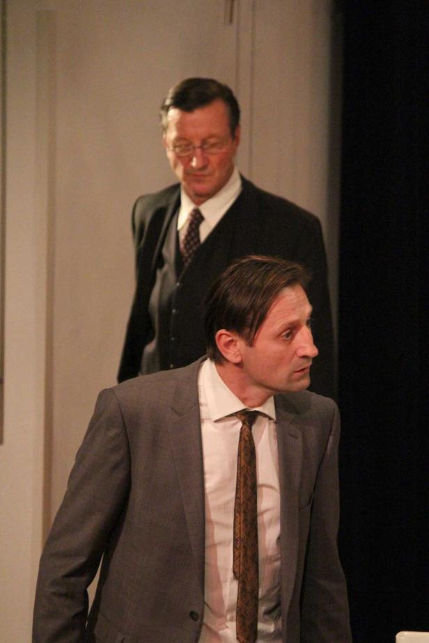 Zwei Männer in Anzügen stehen auf einer Bühne.