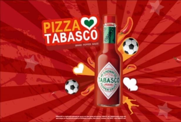 Eine Flasche Tabasco-Sauce vor einem roten Hintergrund mit Fußbällen und dem Schriftzug „Pizza Tabasco“.