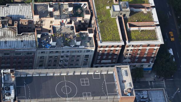 Luftaufnahme von New Yorker Dächern, darunter ein Dachgarten und ein Basketballplatz.