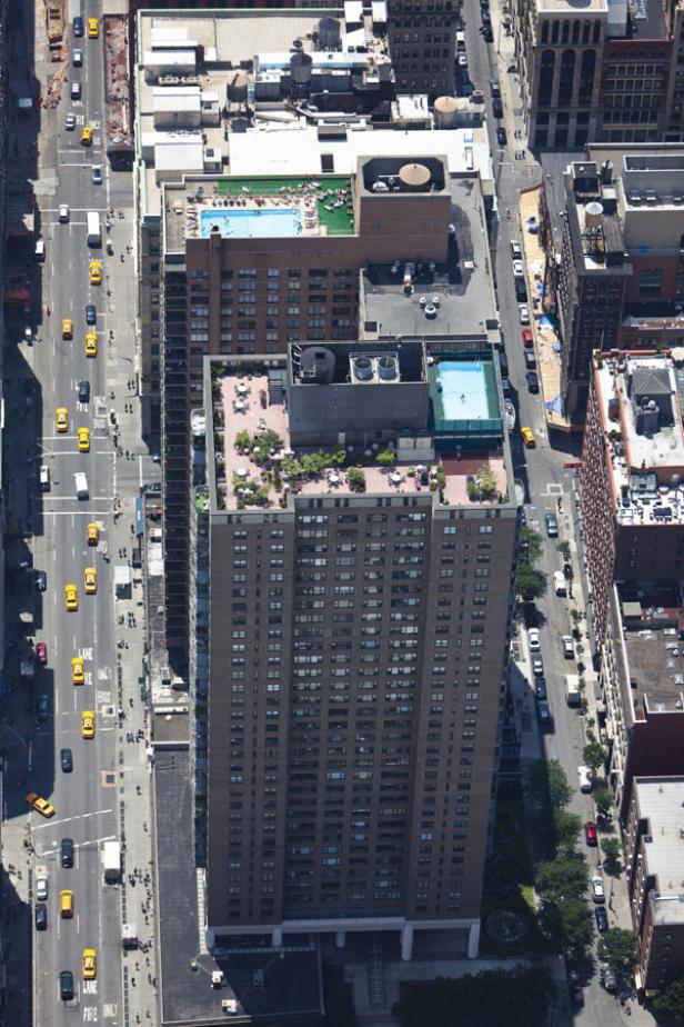 Luftaufnahme eines hohen Gebäudes in New York mit Pools und Dachterrassen.