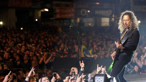 Kirk Hammett von Metallica spielt Gitarre vor einer jubelnden Menschenmenge.