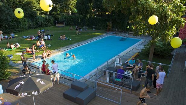 Menschen entspannen sich an einem sonnigen Tag an einem Schwimmbad.
