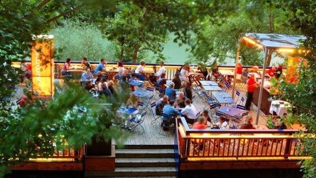 Ein belebtes Restaurant mit vielen Gästen auf einer Terrasse im Grünen.