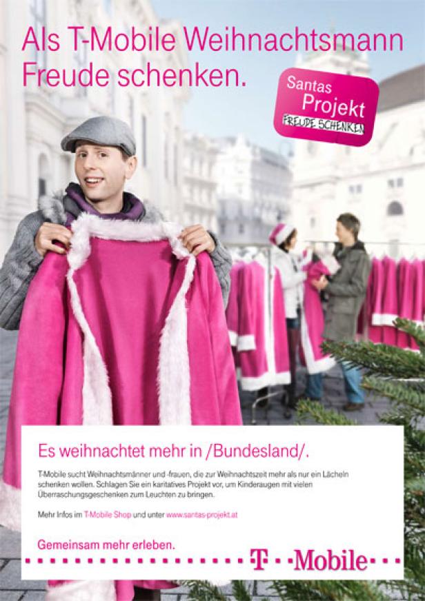 Ein Mann hält einen pinkfarbenen Weihnachtsmannmantel vor einem T-Mobile „Santas Projekt“-Werbeplakat.