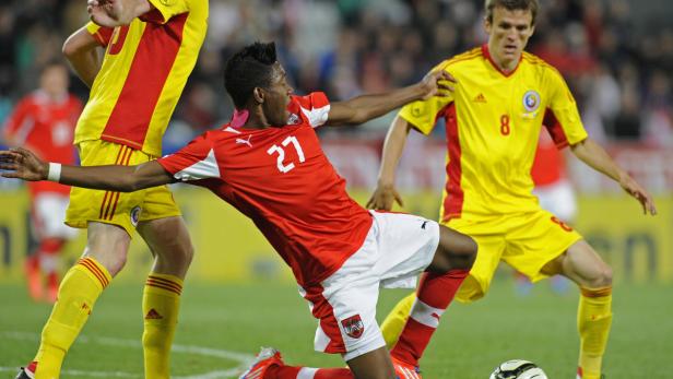 Ein Fußballspieler im roten Trikot mit der Nummer 27 kämpft um den Ball.