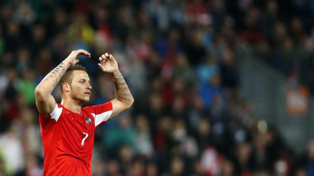 Ein österreichischer Fußballspieler mit Tattoos jubelt vor einer Zuschauermenge.