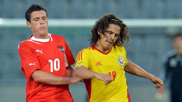 Zwei Fußballspieler im Zweikampf, einer im roten, einer im gelben Trikot.