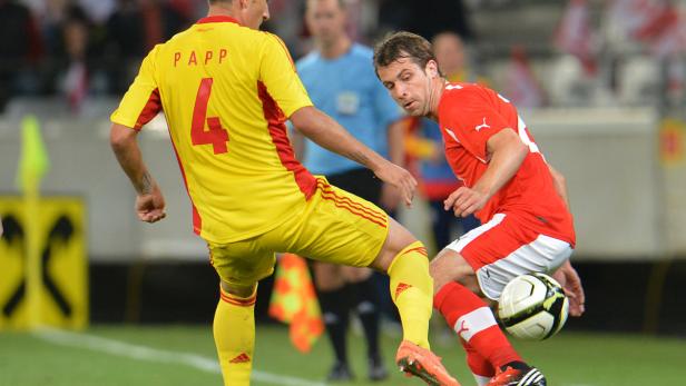 Ein Fußballspieler in Rot kämpft um den Ball mit einem Spieler in Gelb, dessen Trikot mit „PAPP 4“ beschriftet ist.