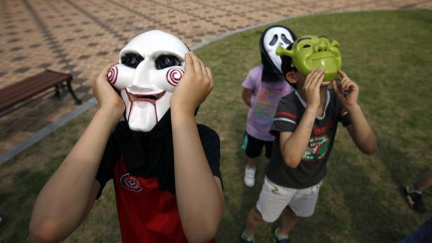 Kinder tragen Masken von Jigsaw, Scream und Shrek.