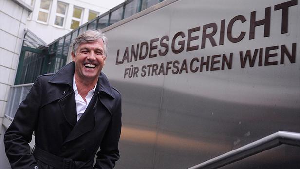 Ein lachender Mann steht vor dem Landesgericht für Strafsachen Wien.